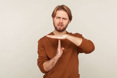 Dur, dur! Huysuz sakallı bir adamın portresi. Tişörtlü, kısa bir jest yapıyor. Teslim tarihinden önce ara verilmesini talep ediyor. Gri arka planda kapalı stüdyo çekimi