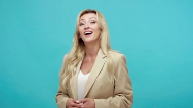 İğneleme ve alaycılıkla kamerayı işaret eden, gülümseyen, insanlarla dalga geçen, egoist neşeli bir kadın. Mavi arka planda kapalı stüdyo çekimi