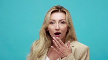 Yakından bakınca, iş stili ceketli, ağzı açık kameraya bakan heyecanlı sarışın kadının portresi, hoş bir şok. Mavi arka planda kapalı stüdyo çekimi