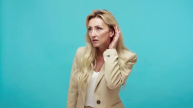 Ceketli, kurnaz, orta yaşlı, sarışın bir kadın özel konuşmalara kulak misafiri oluyor, kişisel sırları öğrenmeye çalışıyor, casusluk yapıyor. Mavi arka planda kapalı stüdyo çekimi