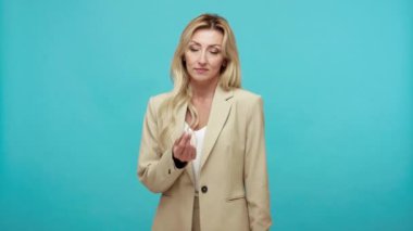 Sarı saçlı fakir, işsiz, yetişkin bir kadının şık ceketinin boş ceplerini gösterecek parası yok, işten çıkarma, kriz, parasal reform. Mavi arka planda kapalı stüdyo çekimi