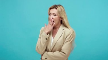 Uykulu, sarışın, iş ceketli, sıkıcı hikâyeler dinleyen, eli boş, ilgisiz, saygısız bir kadın. Mavi arka planda kapalı stüdyo çekimi
