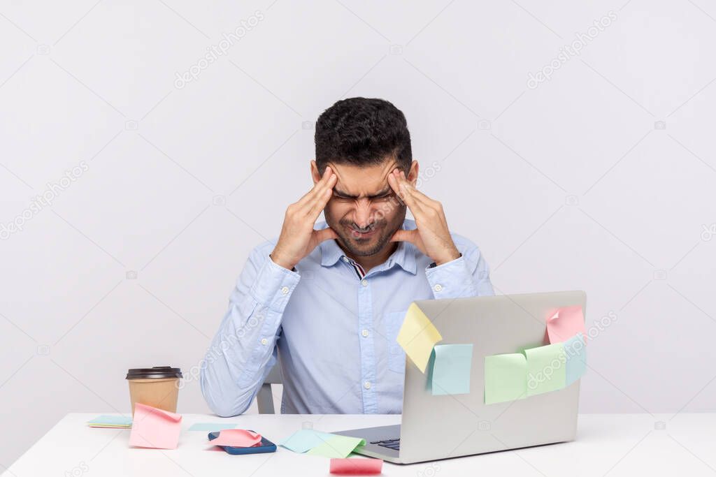 Migraine of stressful job. Depressed man employee sitting in office, clasping head temples, suffering headache and tension, worried about problems at work. studio shot isolated on white background 