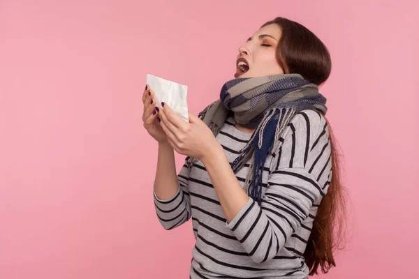 用热围巾包裹的不健康女性的肖像用餐巾纸打喷嚏 出现过敏或流感症状 季节性流感流行 病毒感染 在粉红背景下隔离的室内拍摄 — 图库照片