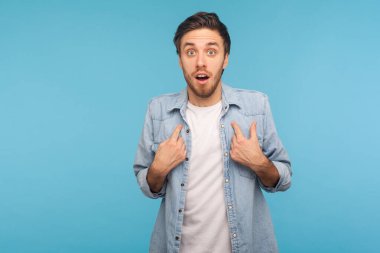 Vay canına, bu benim! İşçi kot gömleği giyen, şaşırmış bir ifadeyle bakan, şaşırmış ve gururlu bir adamın portresi, inanılmaz bir başarı. Stüdyo çekimi izole, mavi arkaplan