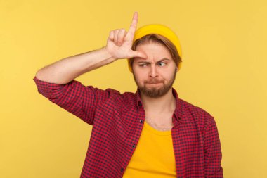 Çok şanssızım! Şapkalı depresif hippi adam ve tişörtünde L işareti var. Alnında ezik bir jest var. Hüsrana uğramış, yenilgi yüzünden üzgün görünüyor. Stüdyoda çekim izole edildi