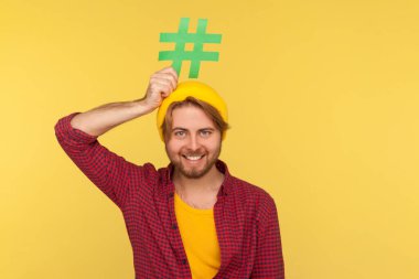 Etiket, internet trendleri. Kareli tişörtlü mutlu hippi adam gülümsüyor ve kafasında viral mesaj sosyal ağının sembolü olan esrar tabelası taşıyor. Sarı arka planda izole edilmiş kapalı stüdyo çekimi