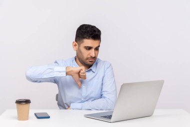 Hoşlanmıyorum! Ofiste çalışan bir işadamı dizüstü bilgisayar ekranına baş parmak işareti gösteriyor. Onaylamadığını belirtiyor, olumsuz işaret ediyor, kötü video çağrısı geri bildirimi yapıyor. Stüdyo çekimi beyaz arkaplanda izole edildi