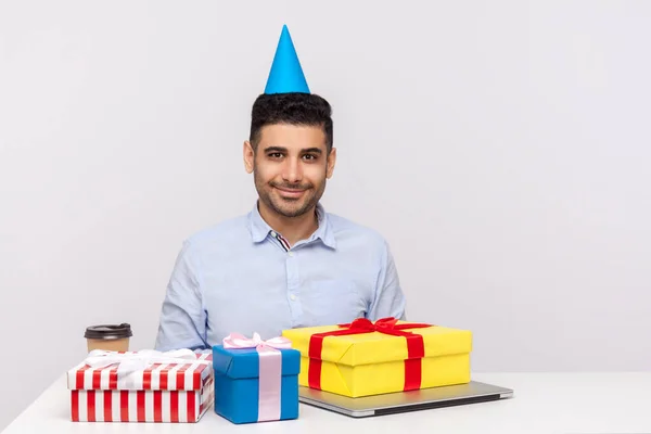 Mann Büroangestellter Mit Parteikegel Sitzt Arbeitsplatz Umgeben Von Geschenkboxen Und — Stockfoto