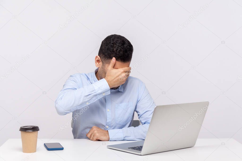 Don't want to look at this! Businessman sitting office workplace with laptop on desk, covering eyes ignoring problems, avoiding watch something unpleasant. studio shot isolated on white background