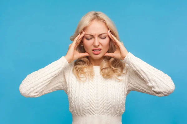 恐ろしい頭痛片頭痛月経前症候群に苦しんでいる悲しい不安ブロンドの女性のマッサージ寺院 青い背景に隔離された屋内スタジオショット — ストック写真