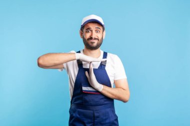 Tulumlu ve eldivenli fazla çalışan tamirci mola veriyor, dinlenmeye ihtiyacı var. Hizmet sektörü mesleği, kurye teslimatı, ev bakımı. Üniformalı işçiler durdular. izole