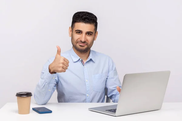 Well done, good job! Happy elegant businessman sitting office workplace, showing thumbs up, like gesture, satisfied with excellent business result. indoor studio shot isolated on white background