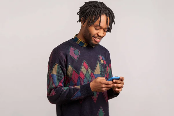 Fröhlich Zufriedener Afrikanischer Mann Mit Dreadlocks Lässigem Sweatshirt Plaudert Smartphone — Stockfoto