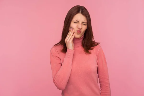 不健康的黑发女人摸着脸颊会感到不愉快的牙痛 口腔炎 牙龈炎 在粉色背景下被隔离的室内拍摄 — 图库照片
