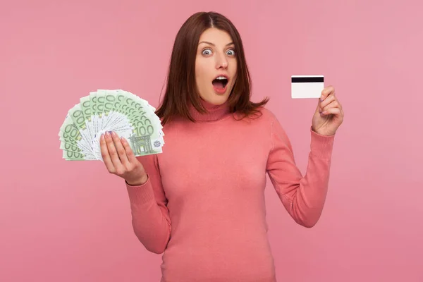 Niezwykle Zaskoczona Brunetka Posiadająca Pokazująca Kartę Kredytową Oraz Fankę Banknotów — Zdjęcie stockowe
