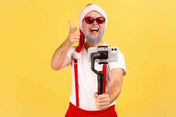 Blogueiro Idoso Positivo Feliz Óculos Sol Traje Papai Noel Apontando — Fotografia de Stock