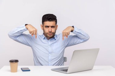 Burada ve şimdi, hemen! Öfkeli patron, masa başında dizüstü bilgisayarla ofis işyerinde oturuyor, parmaklarını yere eğip emir veriyor, kontrol ediyor ve otorite kavramını kullanıyor. Stüdyo çekimi beyaz arkaplanda izole edildi