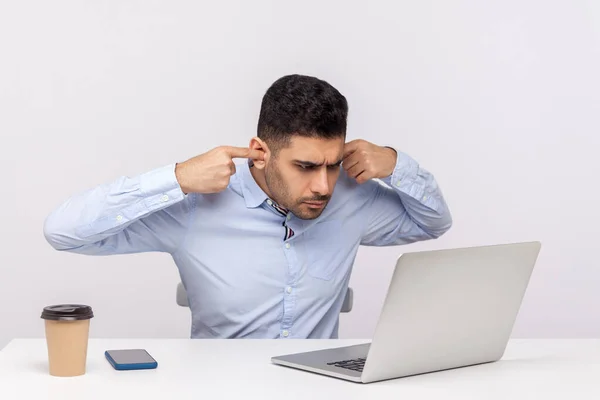 聞きたくない 刺激的なビジネスマンはオフィスの職場に座って ノートパソコンでビデオ通話を話している間に耳を閉じて 不快な仕事会議にオンラインで悩まされています スタジオショット分離 — ストック写真
