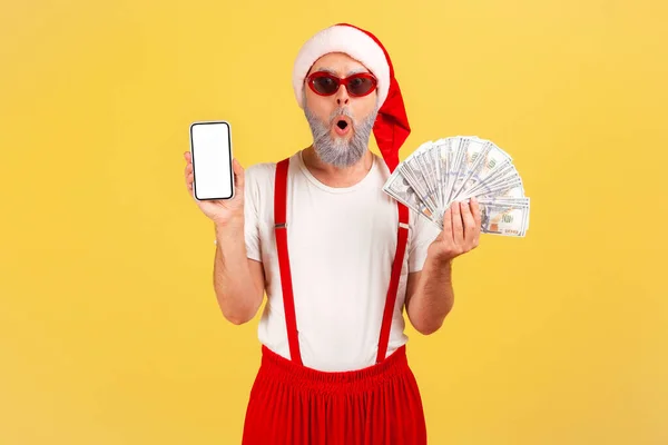 클라우스 모자를 선글라스를 지폐와 스크린 스마트폰 보너스 온라인 뱅킹을 노인이 — 스톡 사진