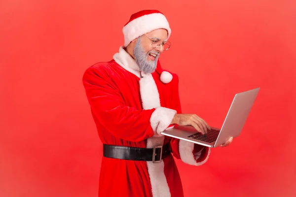 Uśmiechnięty Wesoły Mężczyzna Okularach Kostium Świętego Mikołaja Pracujący Laptopie Wysyłający — Zdjęcie stockowe