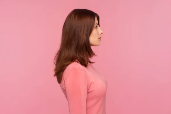 プロフィール肖像画真剣な表情で遠くを見てピンクのセーターで美しい自信のある女性 ピンクの背景に隔離された屋内スタジオショット — ストック写真