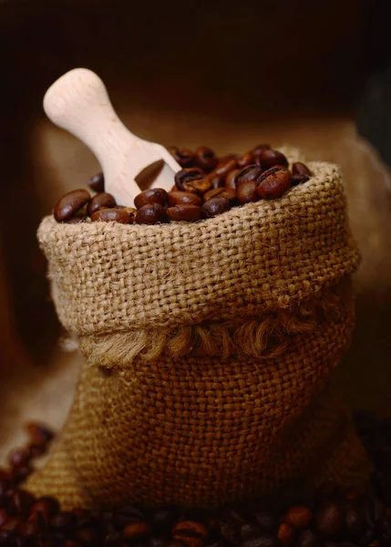 Granos de café en una cucharada de madera y bolsa . — Foto de Stock