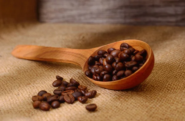 Granos de café en una cucharada de madera . — Foto de Stock