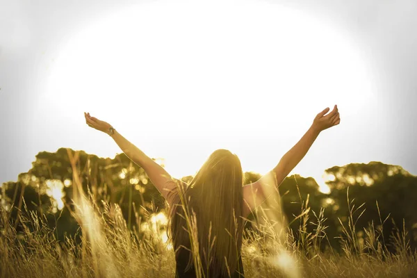 young woman with outstretched arms at wild field