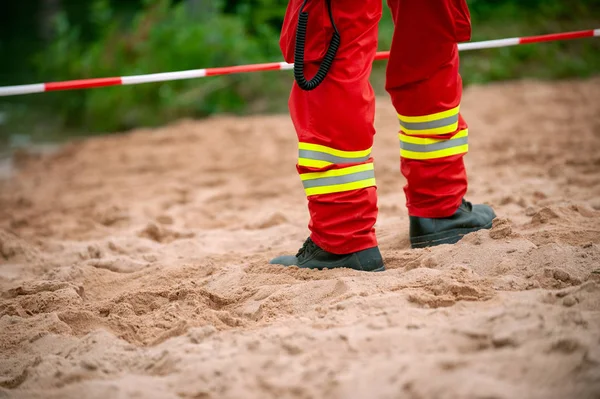 Legs of Rescuer standind on the Sand in front of red and white tape. — Stock Photo, Image