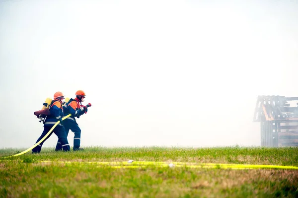 Unga brandmän under utbildning med brandslang genom att släcka branden. — Stockfoto