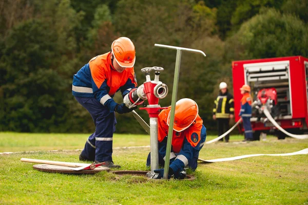 Germany, Baden Wurttemberg, Niederstetten. September 2019. Young firefighters in training, pumping water. — Stock Photo, Image