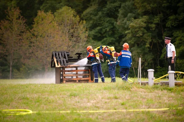 Young firefighters in training with fire hose by extinguishing the fire. — Stock Photo, Image