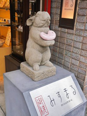 Pembe kalp taşıyan bir tavşanın küçük taş heykeli bir Japon dükkanının önündeki beton kaidede sergileniyor.. 
