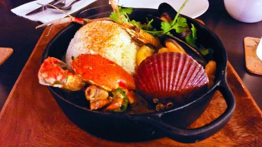 Parlak yeşil bir sos ve bir garnitür taze filizle kaplanmış tavada kurutulmuş deniz tarağı ve yengeç tabağı.. 