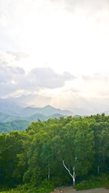 Bereketli yeşil tepeleri, dramatik bulutları ve vadileri aydınlatan güneş ışınlarıyla nefes kesici bir dağ manzarası. 