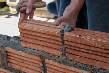 Duvarcı işçisi dış duvara tuğla döşüyordu..