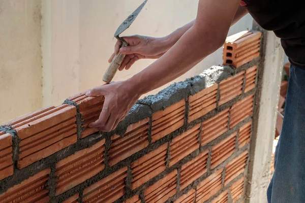 Duvarcı işçisi dış duvara tuğla döşüyordu..