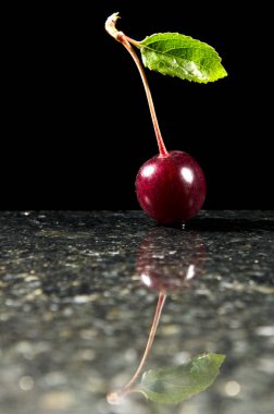 Olgun kırmızı kiraz siyah bir zemin üzerine koyu bir yansıtıcı yüzeyi koyu atmosferik görüntü