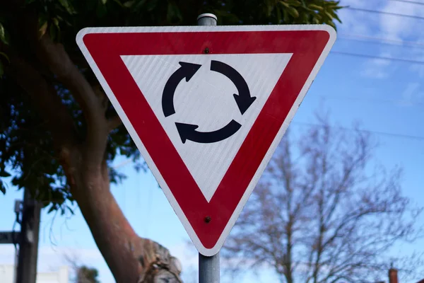 Australian roundabout sign in red triangle shape with three black rounded arrows