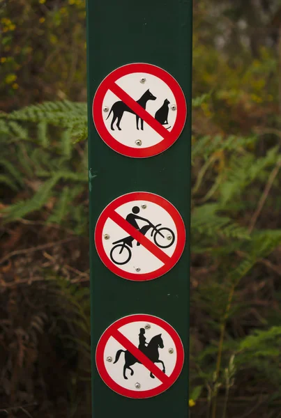 No Dog, No Motor Cycles, No Horse Riding Sign with natural green and brown plants background