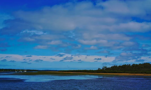 多云的天空和蓝色的水的风景与几艘小船在阴天 — 图库照片