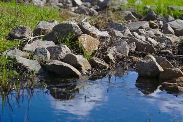 Högar Stenar Och Grus Nära Blå Vatten Soliga Dag — Stockfoto