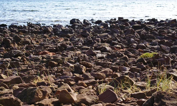 Strand van stenen en water in de achtergrond — Stockfoto