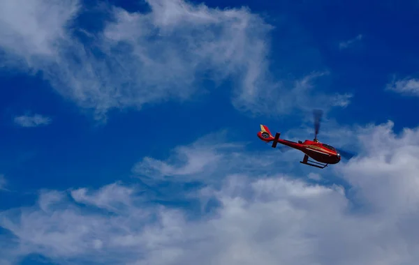 Helicóptero rojo volando con cielo azul y nubes blancas en el fondo — Foto de Stock