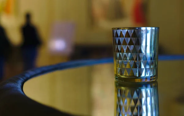 Silver whiskey tumbler on glass top surface