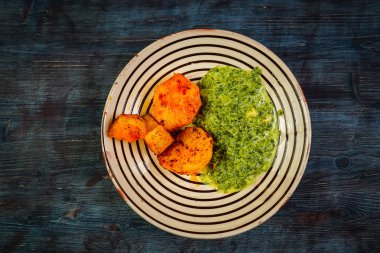 Patates ve ahşap zemin üzerine tabak içinde püre ıspanak pişmiş. 