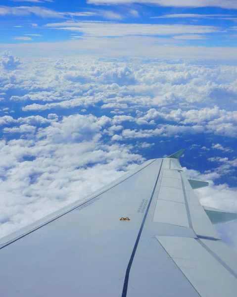 Airplane wing in the sky. View from airplane porthole. Beautiful blue sky with clouds