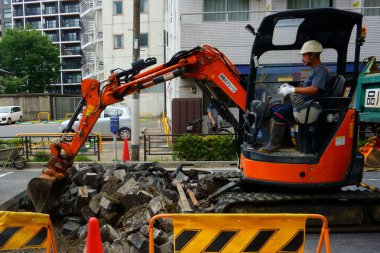 Tokyo, Japonya - 11 Eylül 2018: yol çalışmaları. Eski su boruları değiştirme. Adam işletmek bir mini ekskavatör