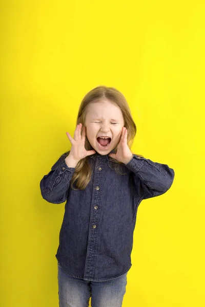 Mała dziewczyna krzyczy emocje na białym tle na żółtym tle. — Zdjęcie stockowe